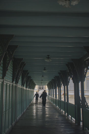Rear view of people walking on footpath amidst buildings