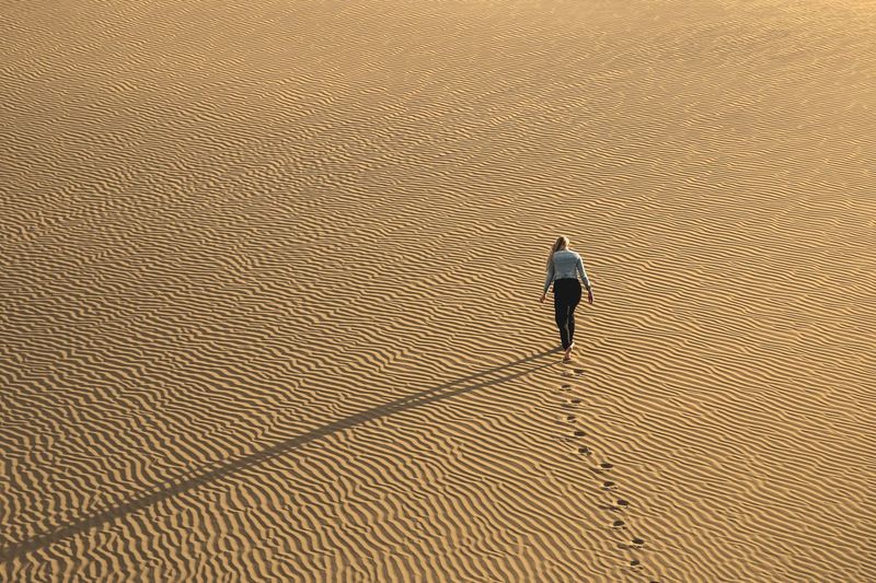 High angle view of woman walking on sand at desert