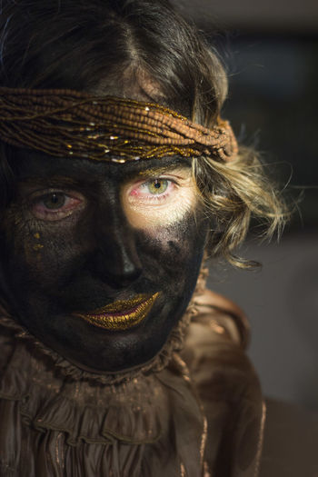 A woman with black painted face and golden clothes, party time, festival, close up portrait, retro