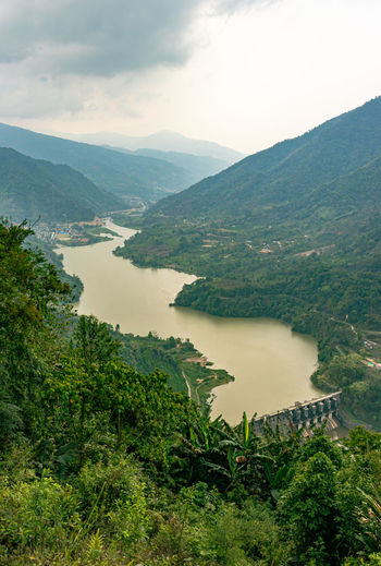 Mountain valley with cloudy sky and river leading at morning from flat angle