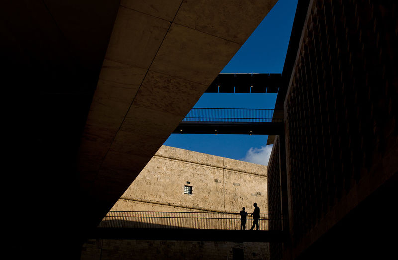 Low angle view of silhouette people standing by building