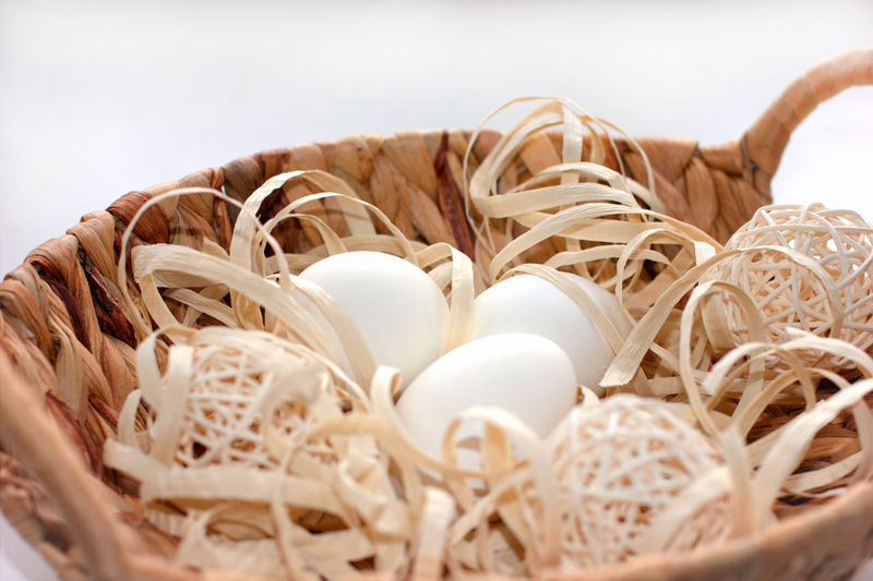 Easter eggs in a basket with wooden decoration. happy easter concept. white eggs in woven basket.