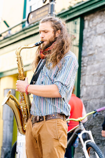 Young man playing saxophone in a crowded street