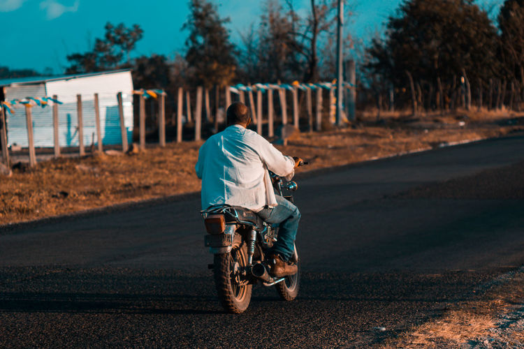 Rear view of man riding motorcycle on road