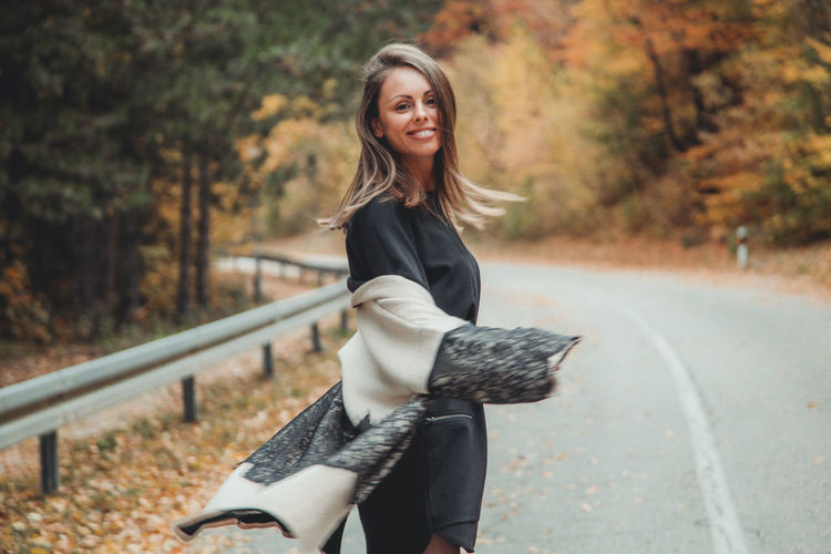 Portrait of woman standing on road during autumn