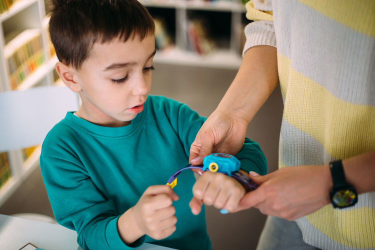 Mom gives her son his first watch. learning to determine the time by the clock.