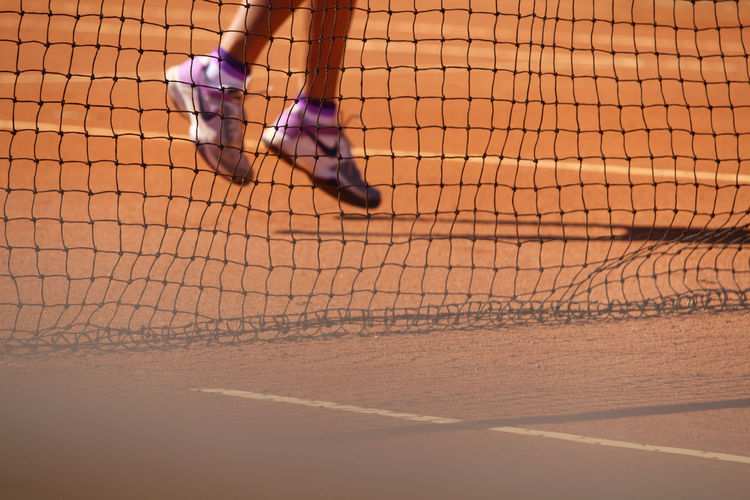Low section of person seen through net at tennis court