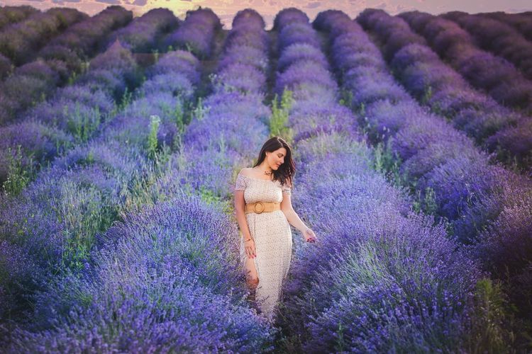 Full length of woman with purple flowers on field