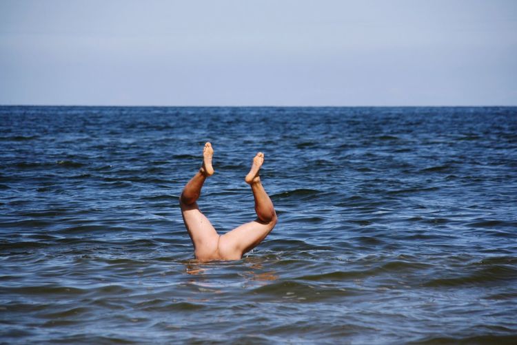 Low section of man in sea against sky