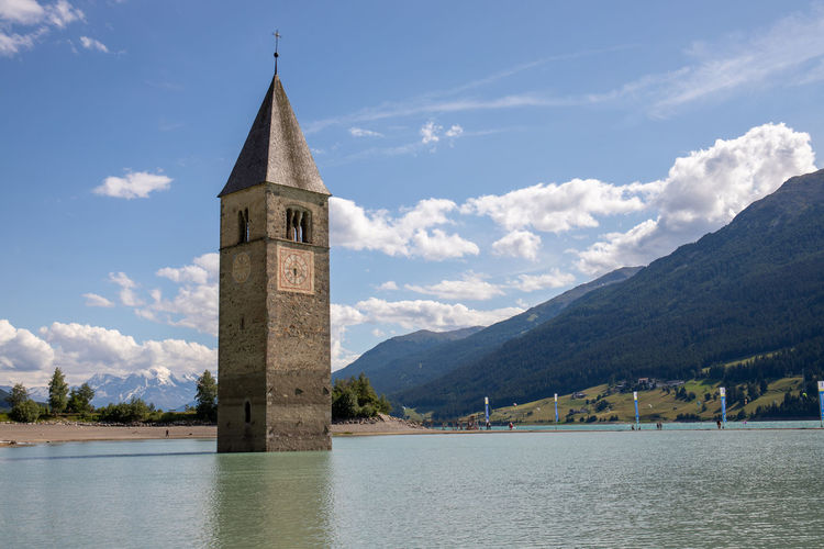 Tower by lake against sky