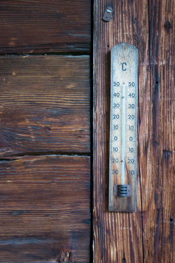 Close-up of weathered thermometer on wooden wall