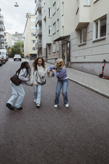 Female friends enjoying while walking on street in city