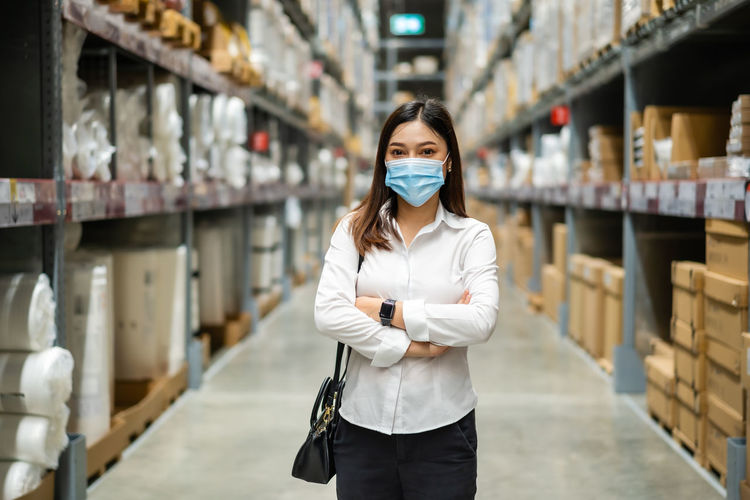 Portrait of woman wearing mask standing in warehouse