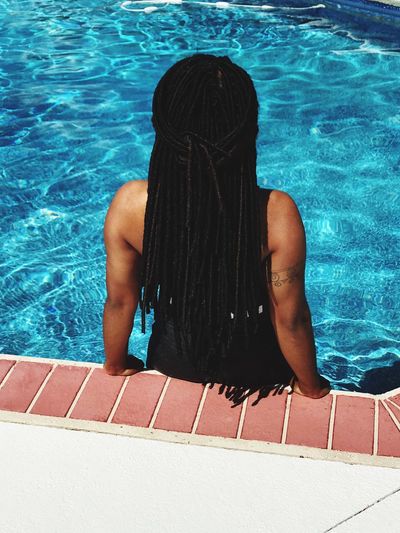 Rear view of woman with dreadlocks in swimming pool