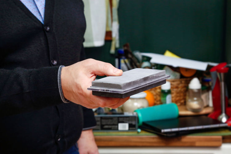 Midsection of businessman holding sharpening stone in workshop