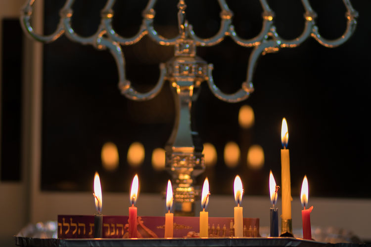Colorful hanukkah candles are lit, black background of the night - the jewish holiday of hanukkah 