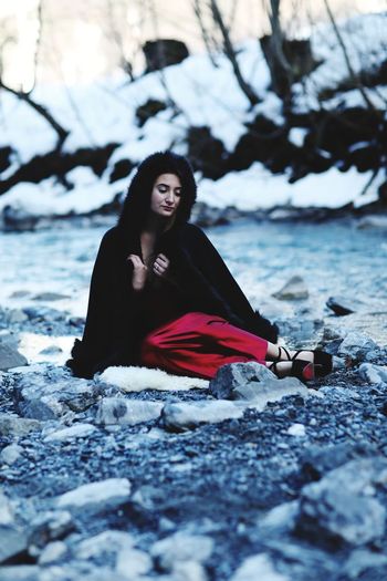 Young woman wearing warm clothing sitting on rocks