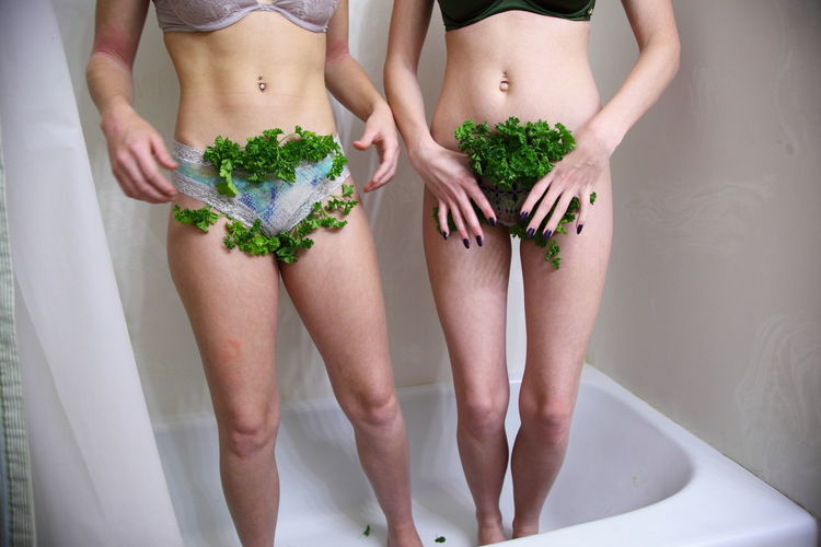 Midsection of woman standing with vegetables in panties standing in bathtub
