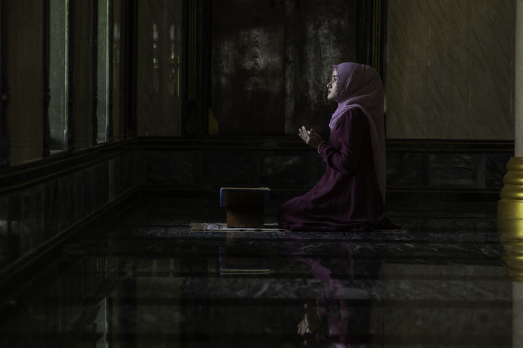 Side view of woman praying in mosque