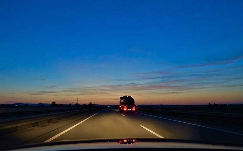 Vehicle on highway against sky during sunset
