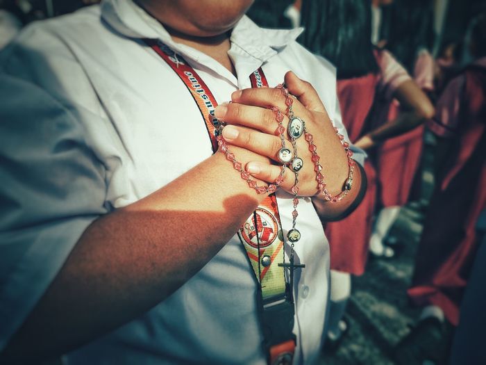 Midsection of man with rosary beads standing outdoors
