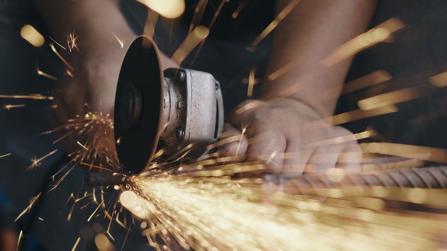 Worker man using electric wheel grind and cutting on steel structure spark from the grinding wheel