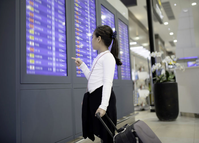 Girl reading arrival departure board at airport