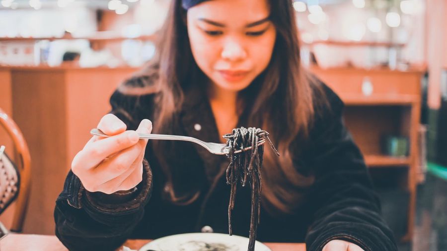 Midsection of woman holding noodles in restaurant