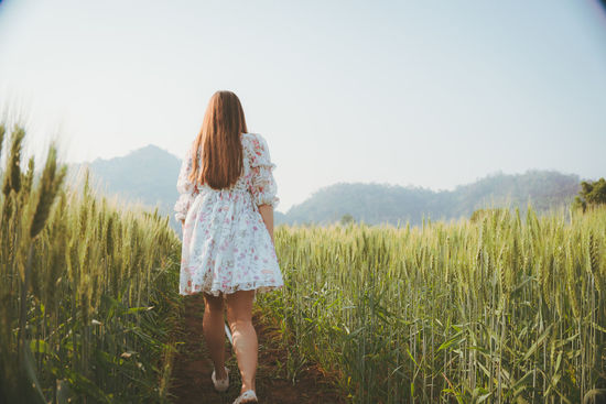 Rear view of woman standing on field against sky