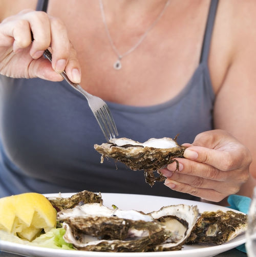 Woman eat with a fork oysters