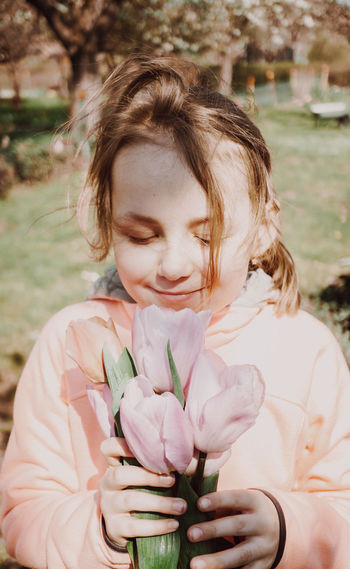 Girl smelling while holding pink tulip flowers