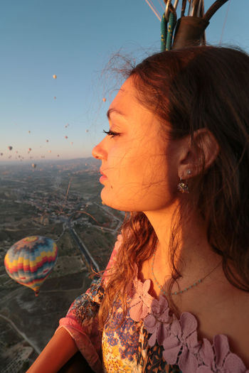 Beautiful girl looking at view from hot air balloon at sunset in cappadocia national park