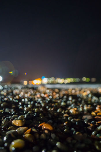 Close-up of pebbles at beach against sky at night