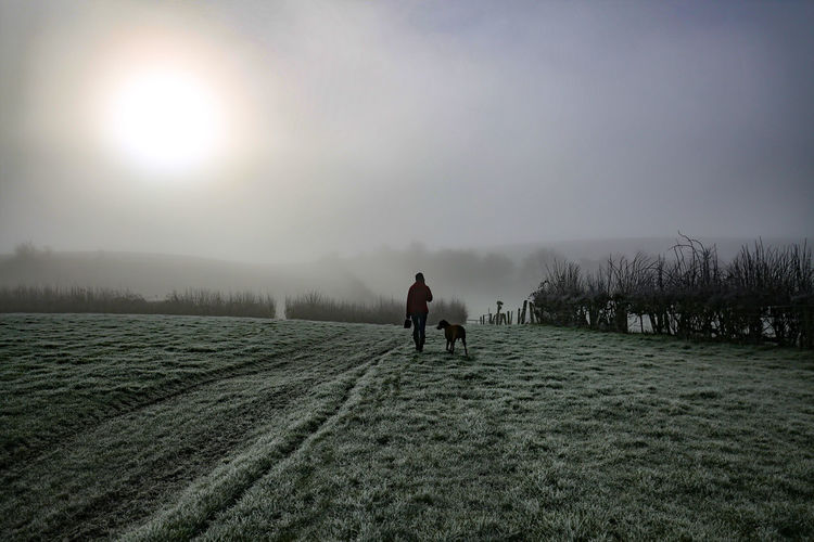 People walking on snowy field against sky during winter