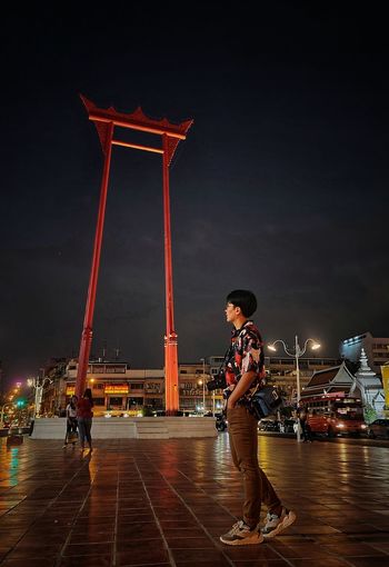Man and woman standing at illuminated city against sky at night