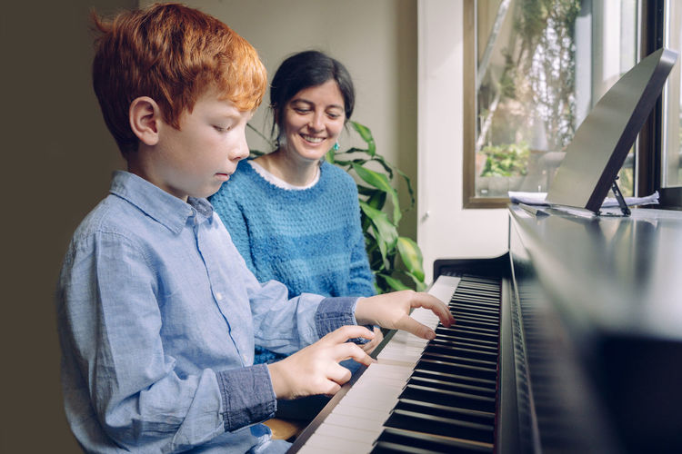 Mother and son playing piano at home