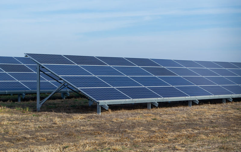 Solar panels on field against sky