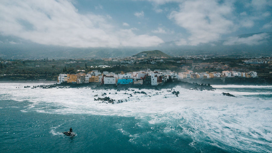 Scenic view of sea by buildings against sky