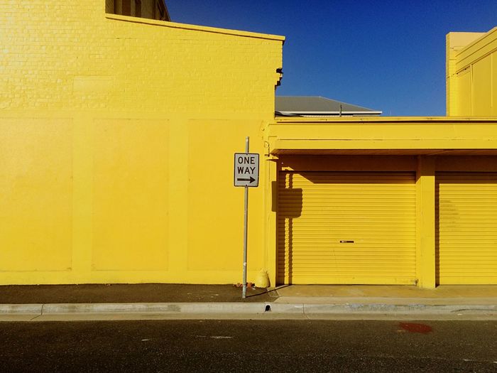 One way sign against yellow building