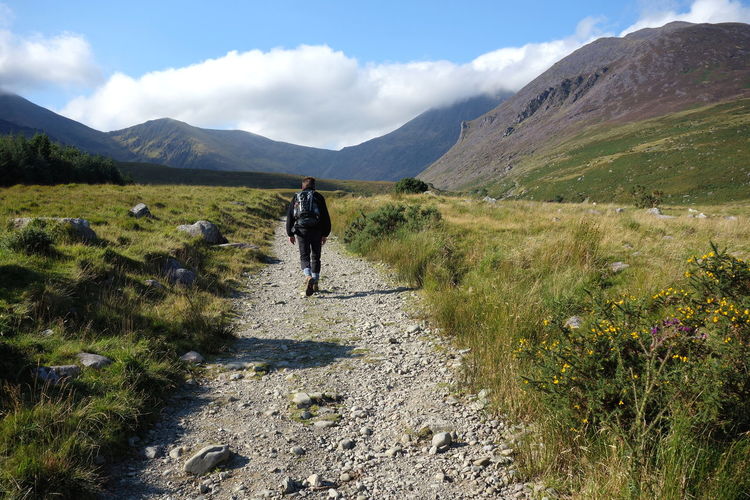 Rear view of man walking on trail against sky