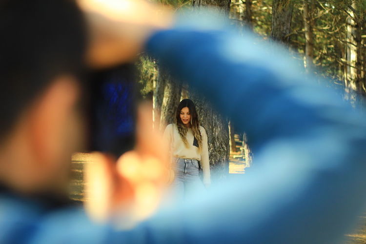 Man photographing young woman at forest