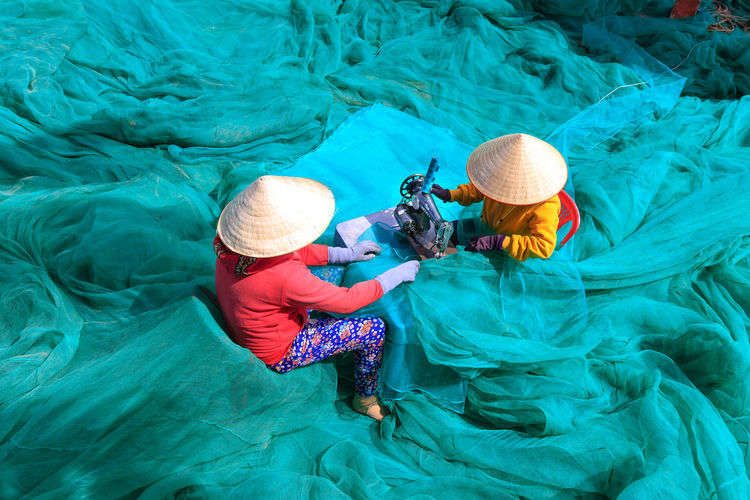 High angle view of women sewing fishing net