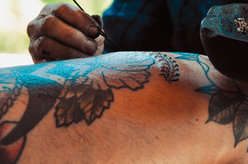 Cropped image of person tattooing on human skin