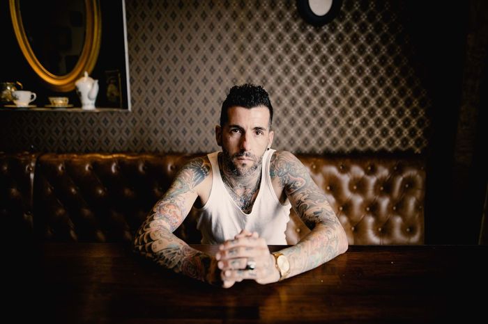 Portrait of man with tattoo sitting on sofa at table