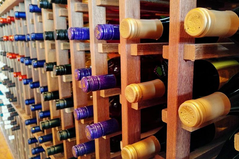 Close-up of wine bottles on wooden rack at warehouse
