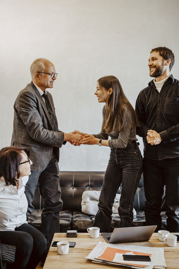 Male advisor doing handshake with female programmer in office
