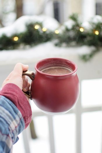 Close-up of hand holding coffee cup with snow