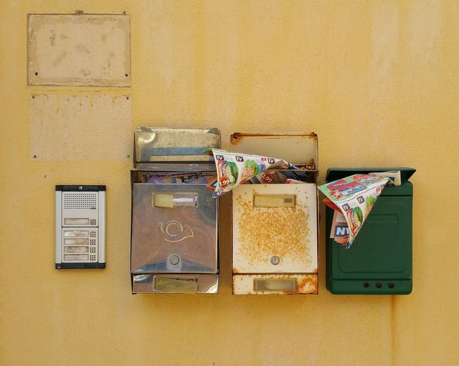 Magazines in mailbox against yellow wall