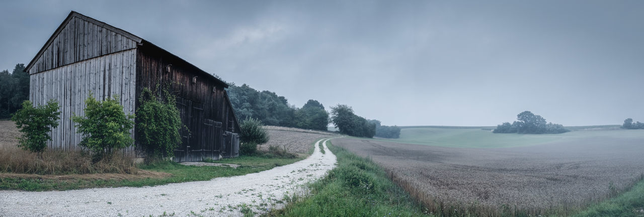 Panoramic view of road amidst field against sky