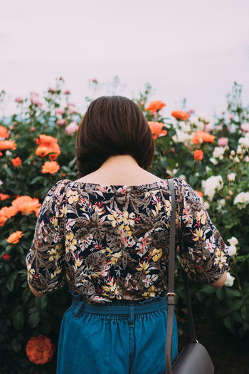 Rear view of person standing by flowering plants